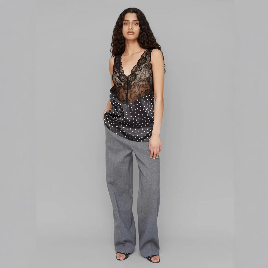 Stilren V-hals spaghetti topp for damer, svart med hvite prikker og elegante blondedetaljer. Casual chic.
