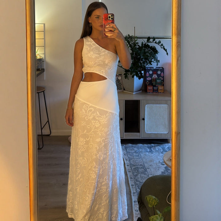 Elegant hvit dame maxikjole med asymmetrisk snitt, blomsterdetaljer og V-hals. Perfekt festkjole.