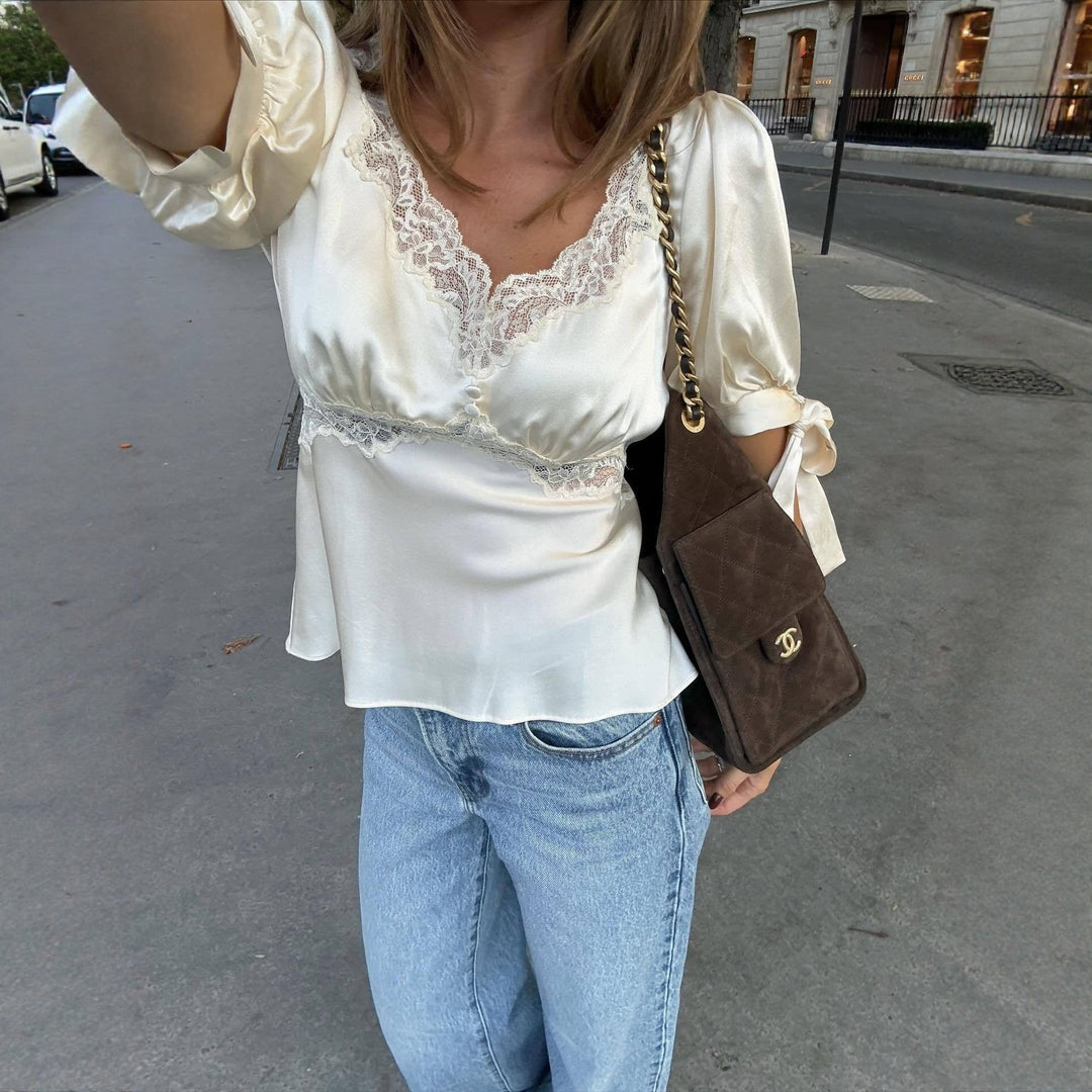 Elegant damesatinbluse med blondekant og lange ermer, perfekt for fest eller kontorstil.