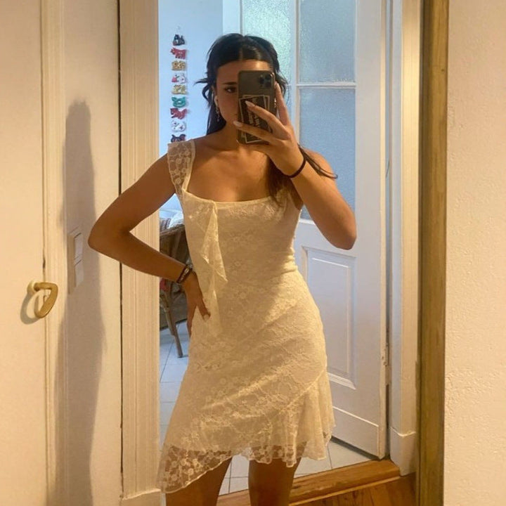 Elegant hvit damekjole med asymmetrisk snitt og spissdetaljer, perfekt som festkjole eller selskapskjole for sommeren.