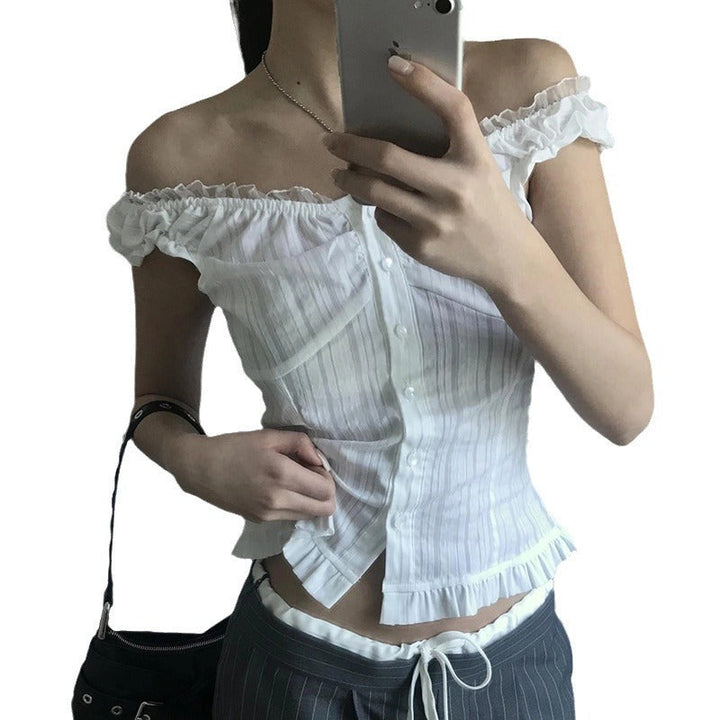 Modell iført hvit off-shoulder damebluse med volangkant. En stilbevisst sommerbluse for en elegant look.