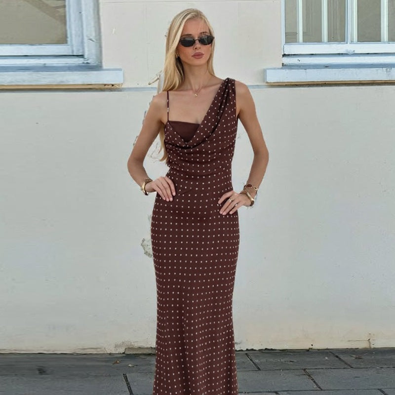 Elegant dame maxikjole med asymmetrisk utringning og klassiske prikker. Perfekt for fest eller sommer.
