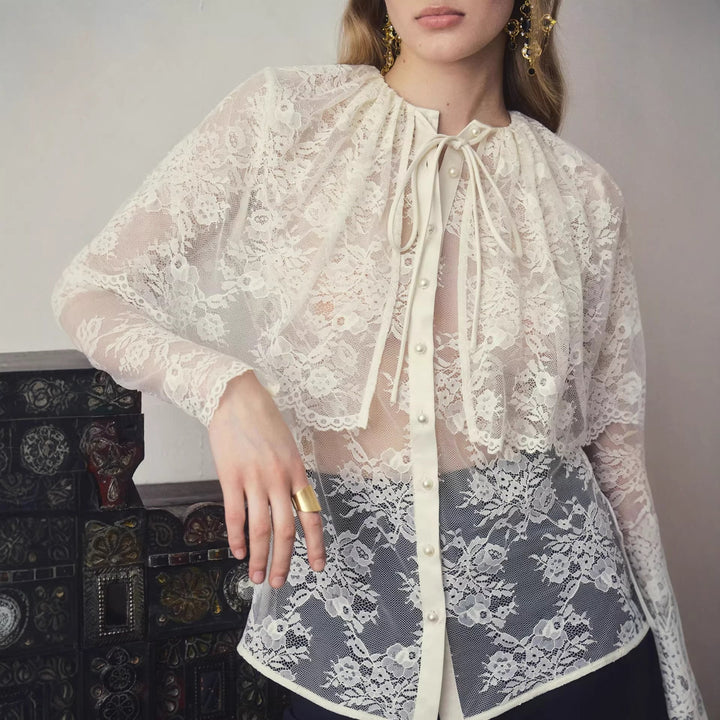 Elegant hvit bluse med stilfull sløyfe og transparente partier, en allsidig overdel for dame.