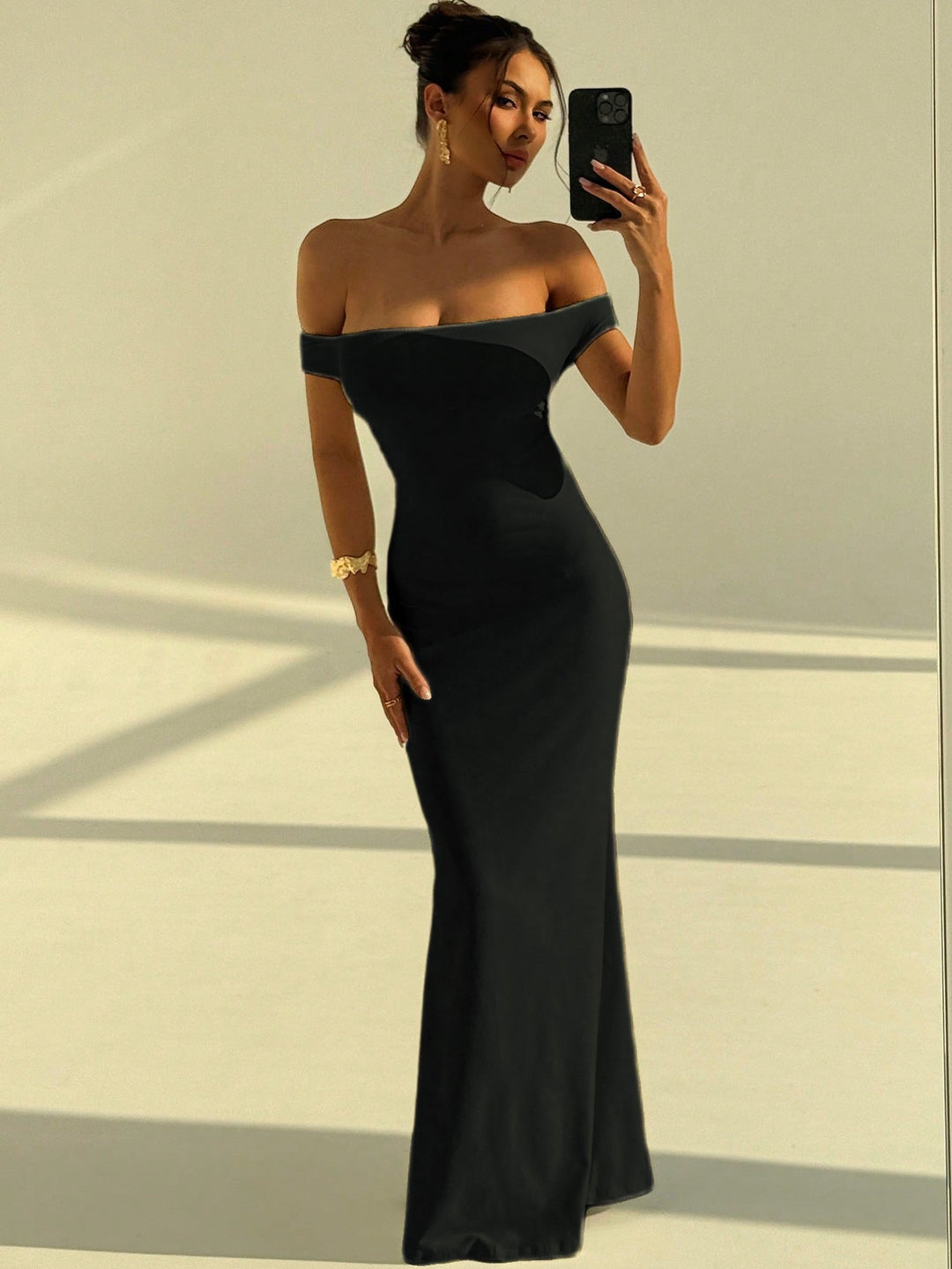 Kvinne poserer i en lang, elegant off-shoulder maxikjole, perfekt for et stilig kveldsantrekk.