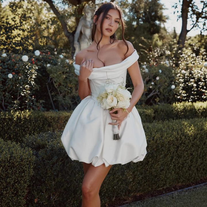 Feminine hvit damekjole; offshoulder snitt, voluminøst skjørt. En lekker sommerkjole for selskap og fest.