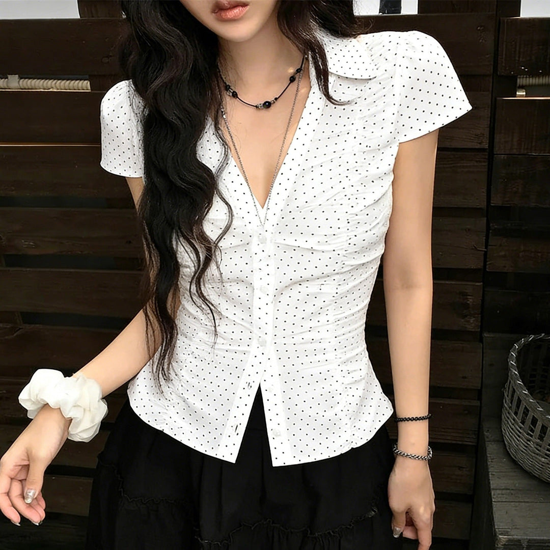 Feminine kortermet damebluse med volanger og prikker for en klassisk stil; ideell for casual chic sommerantrekk.