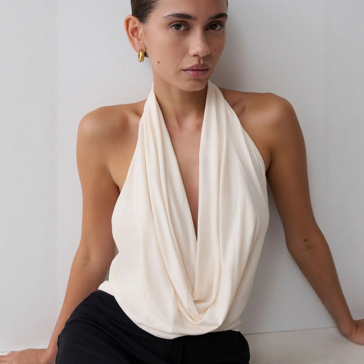 Elegant halterneck-topp for dame med dyp utringning, perfekt for fest og sommer. Stilren og ermeløs.