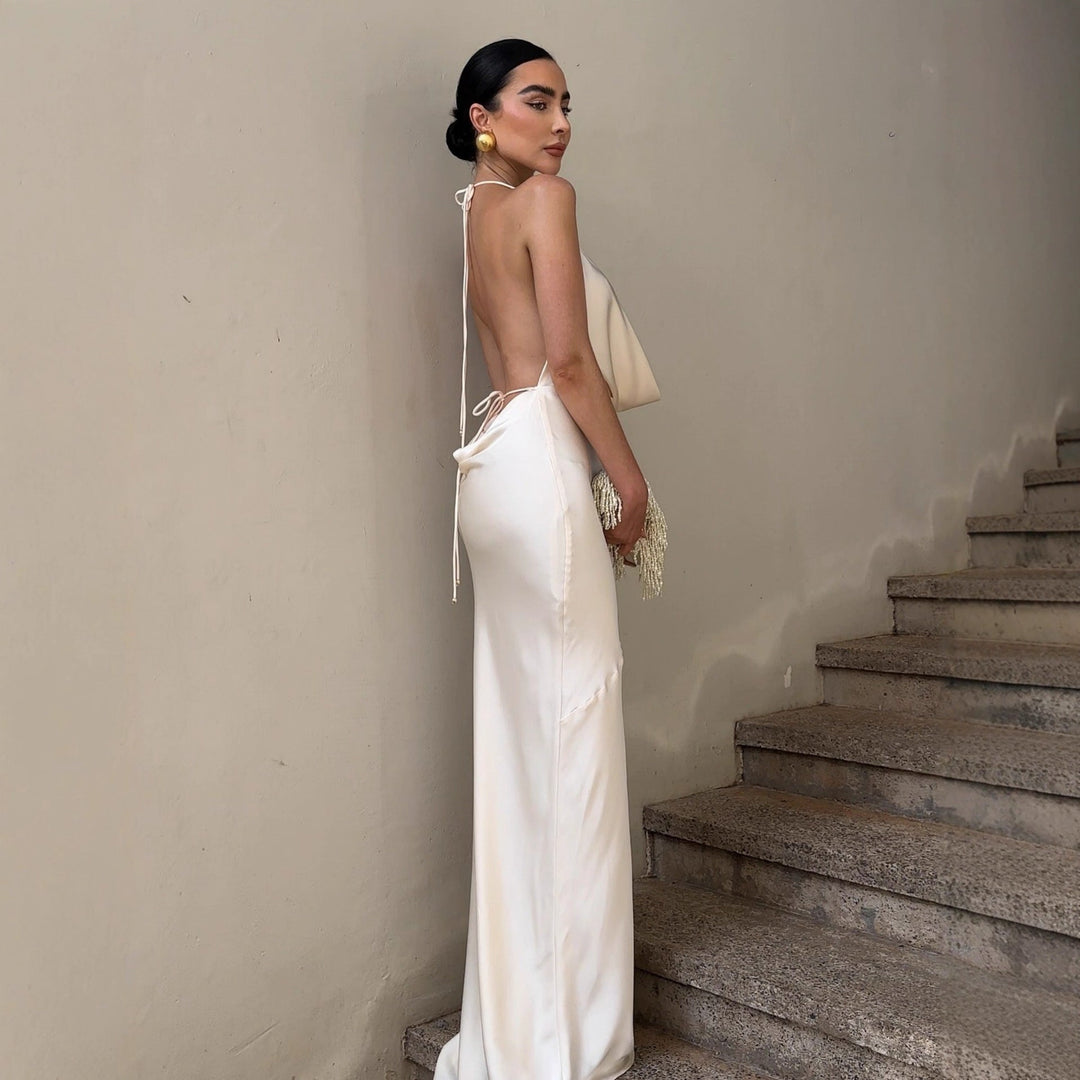Elegant lang hvit damekjole med dyp rygg og omslagsdesign, passer til bryllup, galla og spesielle anledninger.