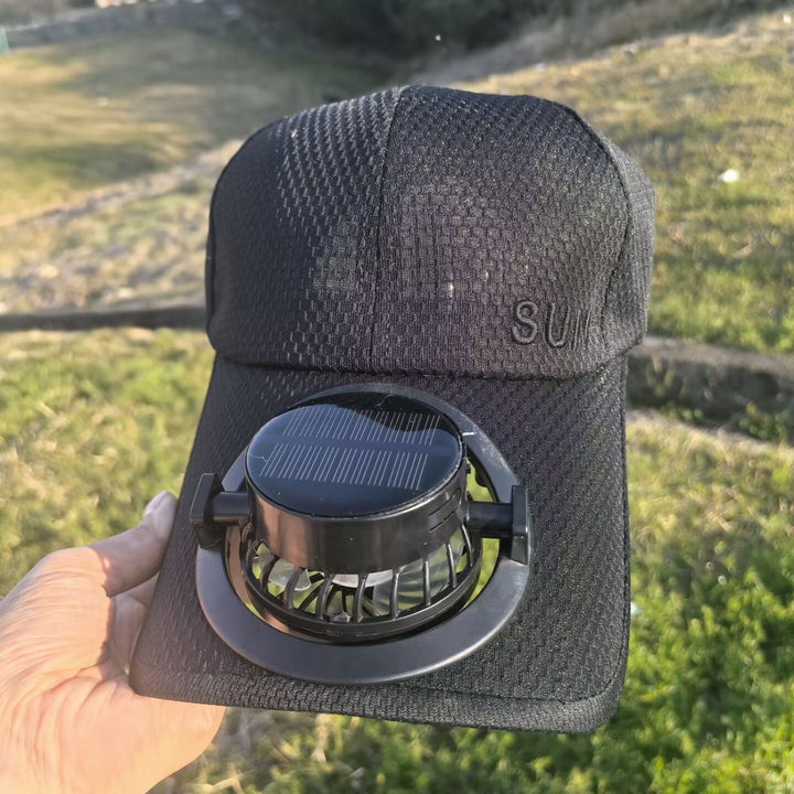En bruker med kjølende baseballcaps, nyter frisk luft fra viften under en utendørsaktivitet.