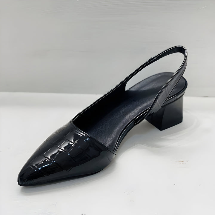 Detaljbilde av elegant slingback pump i svart, viser spiss tå, lav hæl og komfortabel stropp.