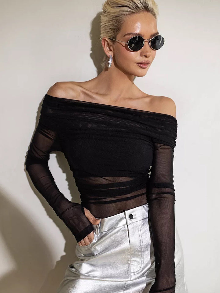 Svart elegant off-shoulder topp med lange ermer og feminine detaljer. Perfekt for en sofistikert look.