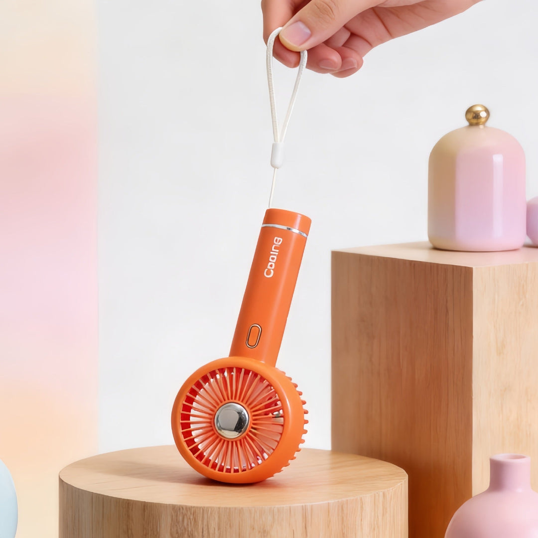 Kompakt oppladbar reisevifte i oransje, USB-drevet for enkel lading og effektiv personlig kjøling.