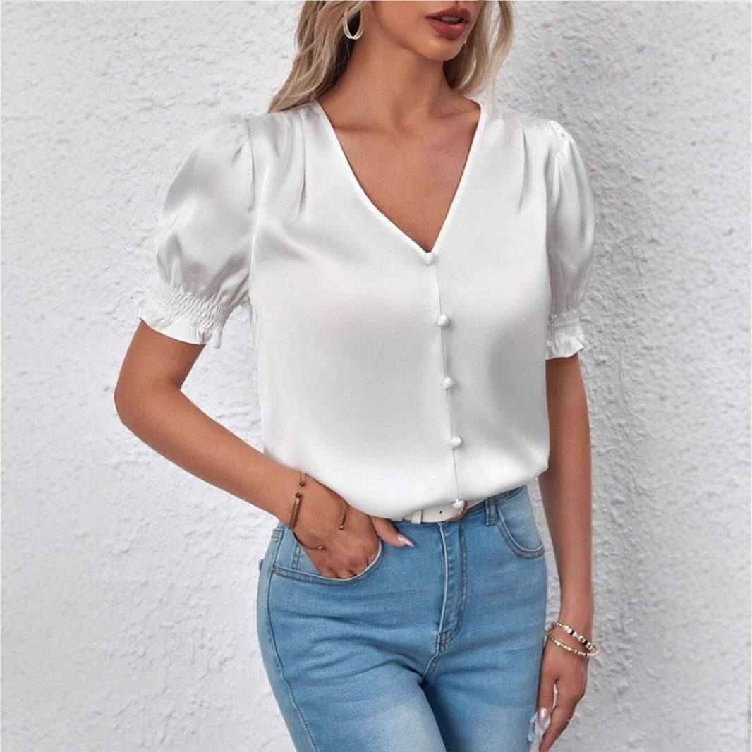 Elegant damebluse med stilige puffermer og diskret knappeliste, perfekt for kontor og fest. Mote.