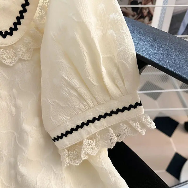 Motevennlig festtopp: Elegant damebluse med karakteristisk Peter Pan-krage og voluminøse puffermer.