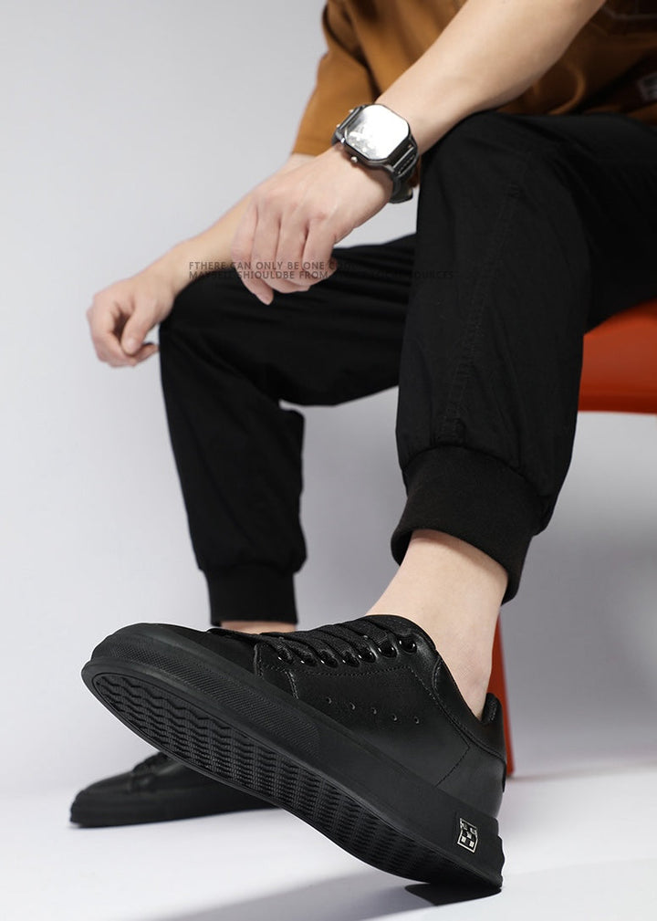 Detaljert bilde av tekstur og design på svarte/hvite høydeøkende menns sneakers.