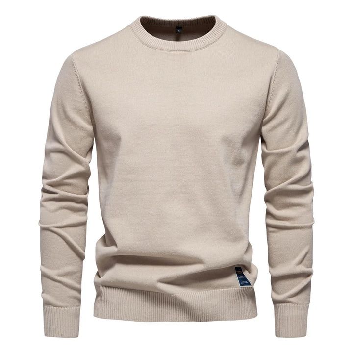 Mann iført ensfarget herregenser i ullblanding, klassisk rund hals. Avslappet og elegant stil.