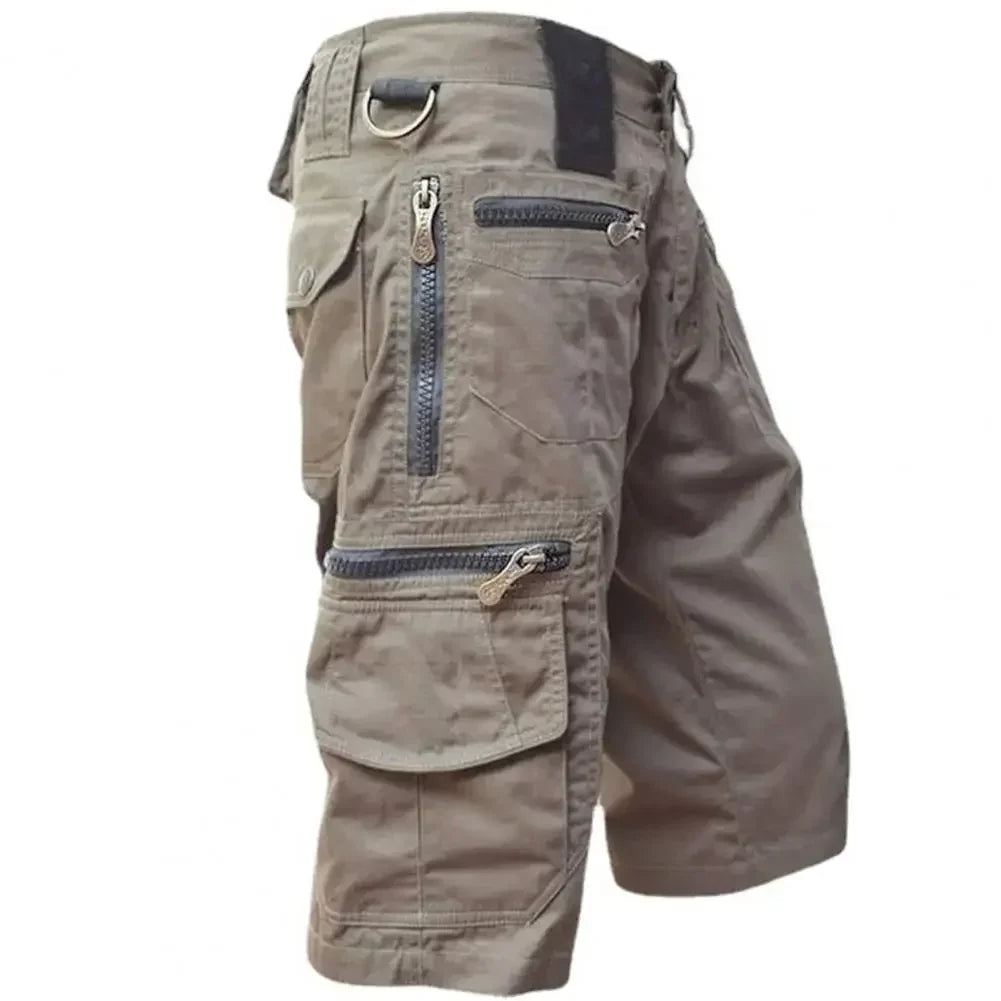 Mann i taktiske herreshorts med flerlommer i militærstil. Perfekt sommershorts for utendørsaktiviteter.