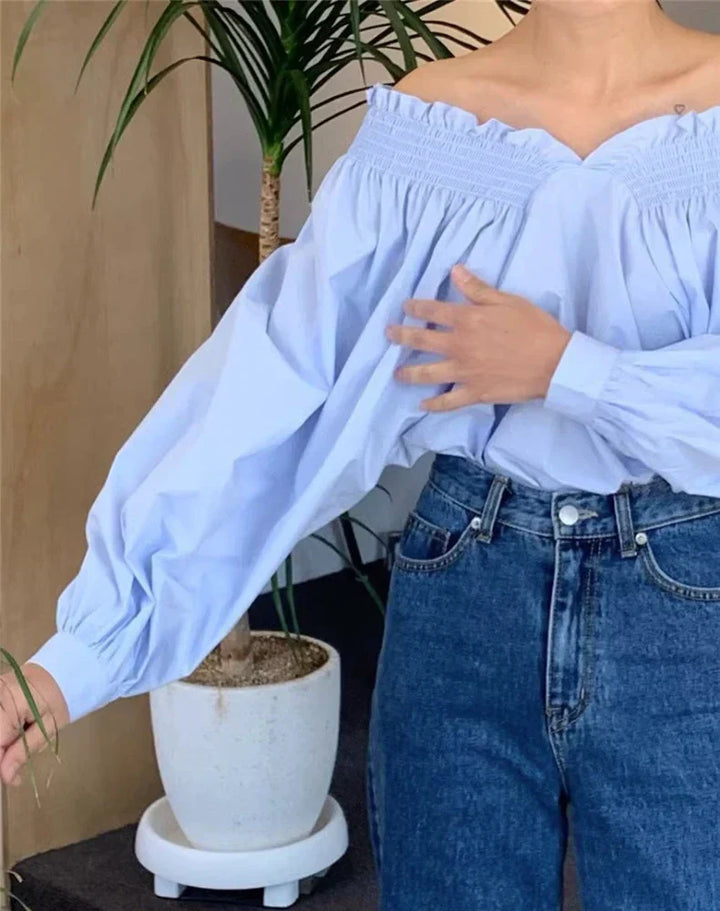 Kvinne iført sexy langermet off-shoulder damebluse. Moderne vår- og høstklær.