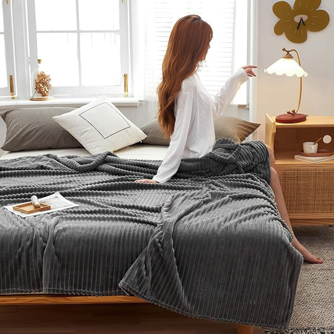 Hjørnedetalj på stripet flanellpledd, viser kvalitet og myk polyesterkorallfleece.