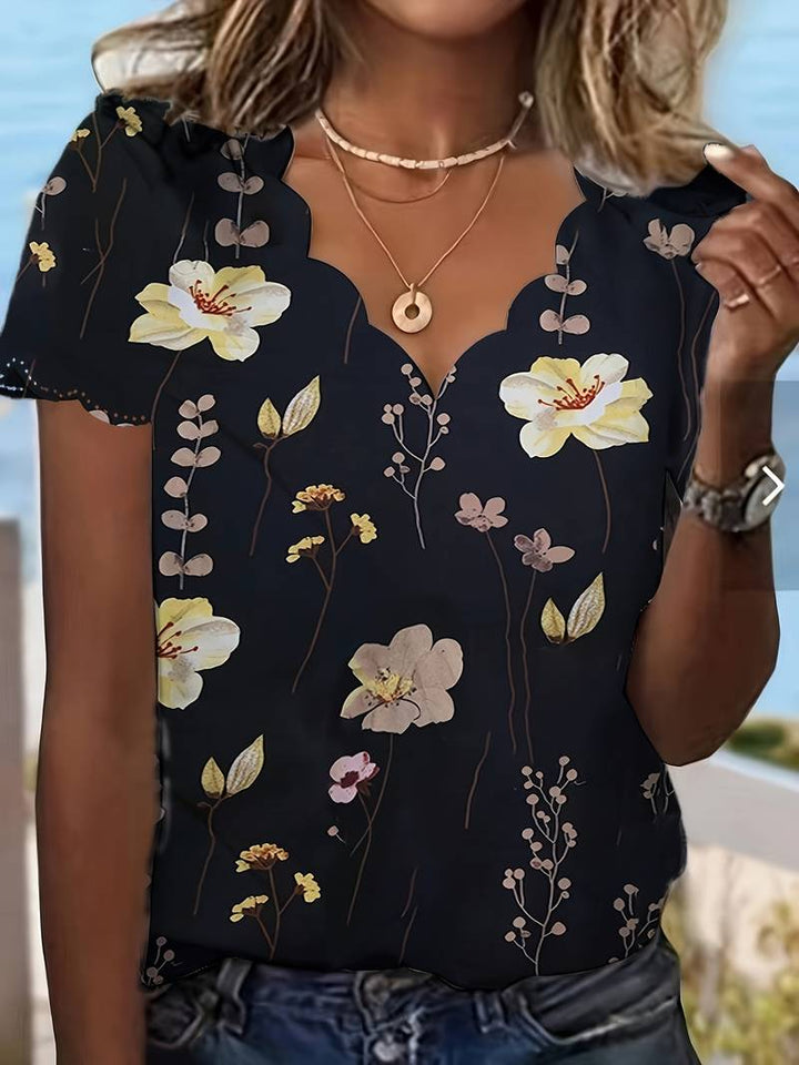 Nærbilde av den myke stoffteksturen og det detaljerte blomstertrykket på dameblusen.