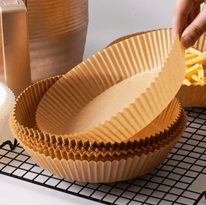 Hånd plasserer non-stick bakepapir i airfryer. Klar for enkel, ren og sunn matlaging.