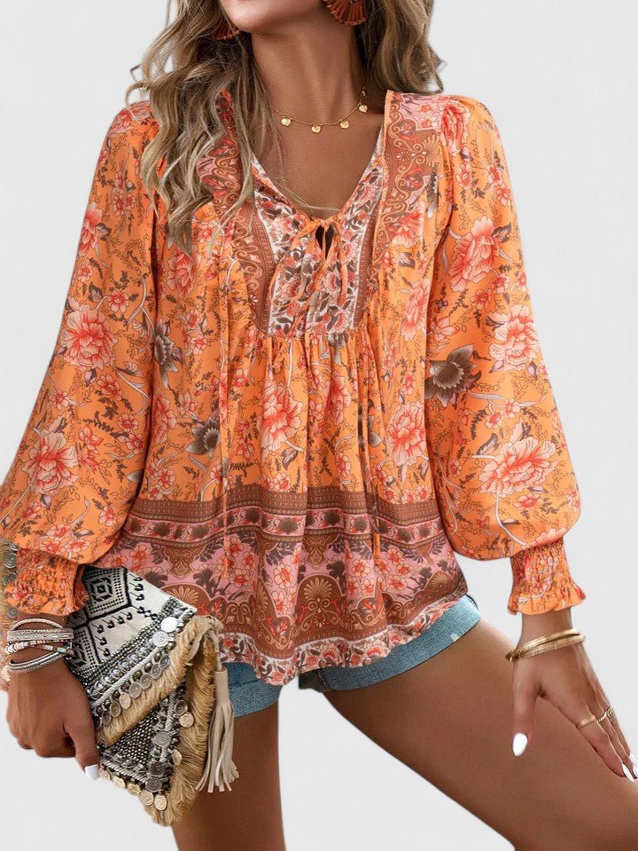 Sommerlig damebluse i boho-mote med fargerikt blomstertrykk, V-hals og moderne puffermer.