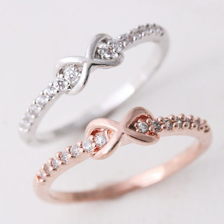Nærbilde av elegant infinityring i sølv på finger, smykke til dame og datter.
