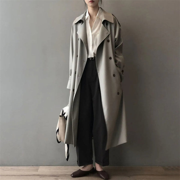 Dame trenchcoat i grå farge, vanntett og dobbelspent. Tidløs stil for elegant beskyttelse.