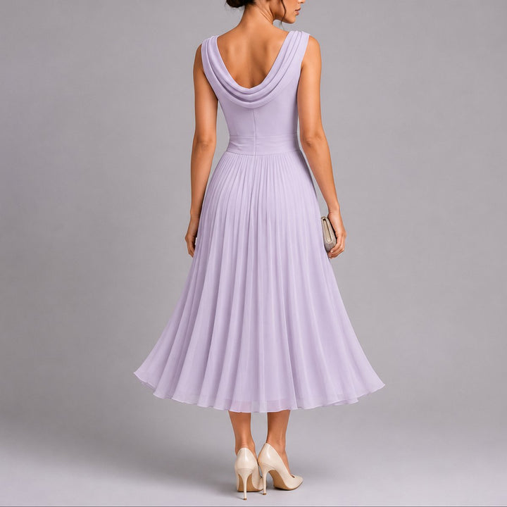 Ermeløs, formell damekjole med plissert skjørt. Tidløs og elegant festkjole for høstbryllup.