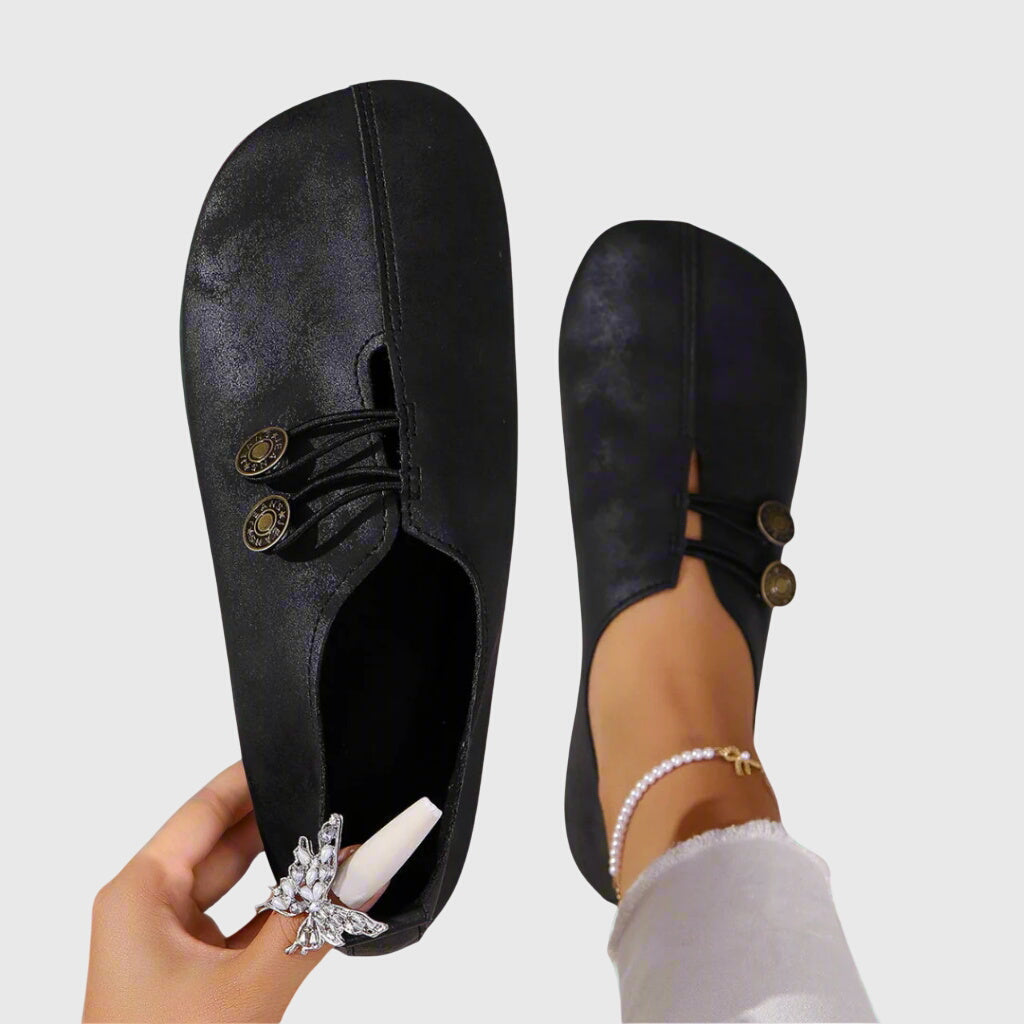 Stilrene flate slip-on sko til dame med unik knappdetalj, perfekt for vårantrekk.