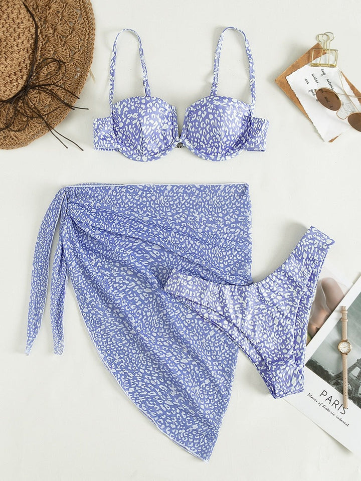 Ryggvisning av komfortabel tredelt bikini med blomstermønster og flytende strandskjørt. Dame strandmote.