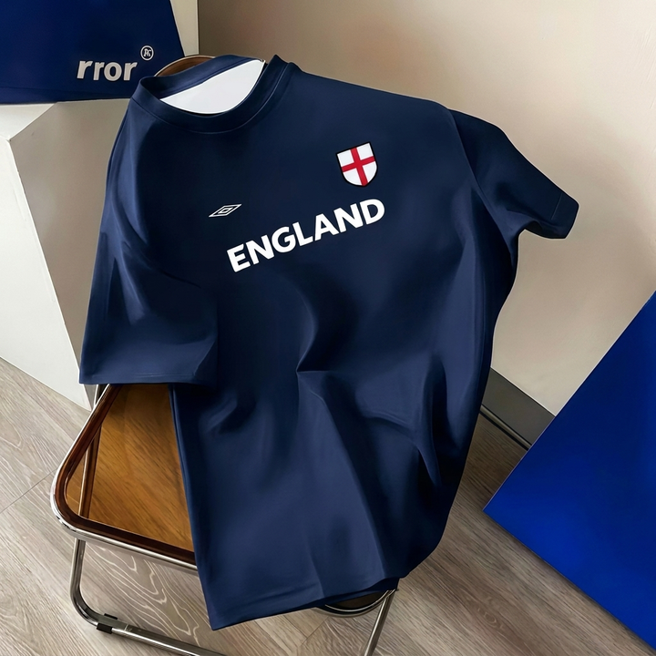 Mann poserer i retro England fotballskjorte i pluss størrelse. Komfortabel og stilig for fritid.