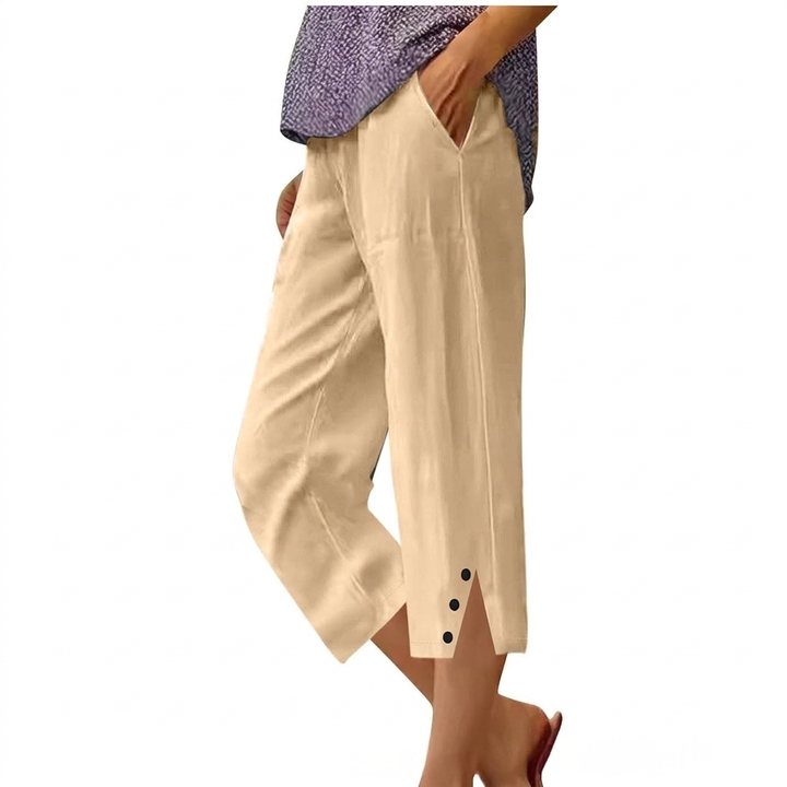 Modell iført elegante damebukser med høy midje, løs passform og lommer. Ideell for vår og sommer.