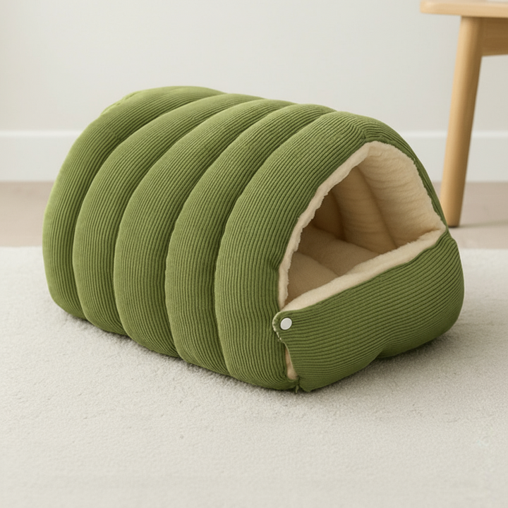 Liten hund hviler avslappet i det varme hundehuset. Trygg og myk kjæledyrseng for innendørs bruk.