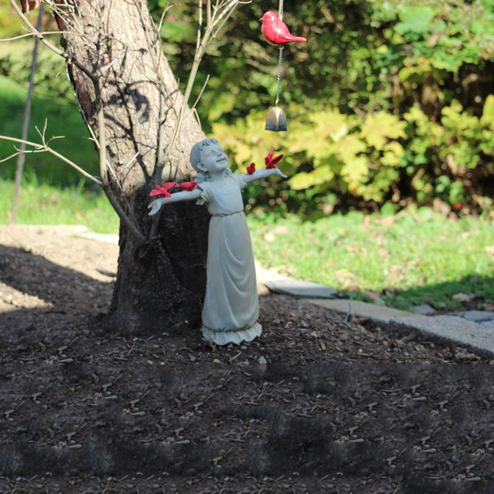 Jentestatue plassert blant grønne planter, en flott hagefigur som beriker hagedekoren.