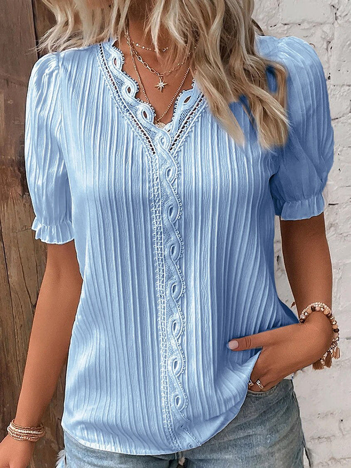 Dame sommerbluse med løs passform, V-hals og trendy puffermer. Elegant sommertopp for alle anledninger.