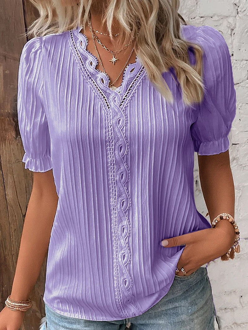 Kvinne iført elegant sommerbluse med V-hals og puffermer. Komfortabel damebluse med blonder.