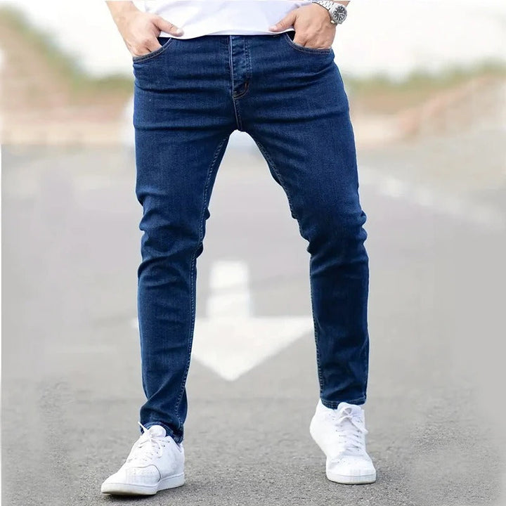 Mann iført blå skinny-jeans med stretch. Viser den moderne slim fit-passformen og komfortable stil for menn.
