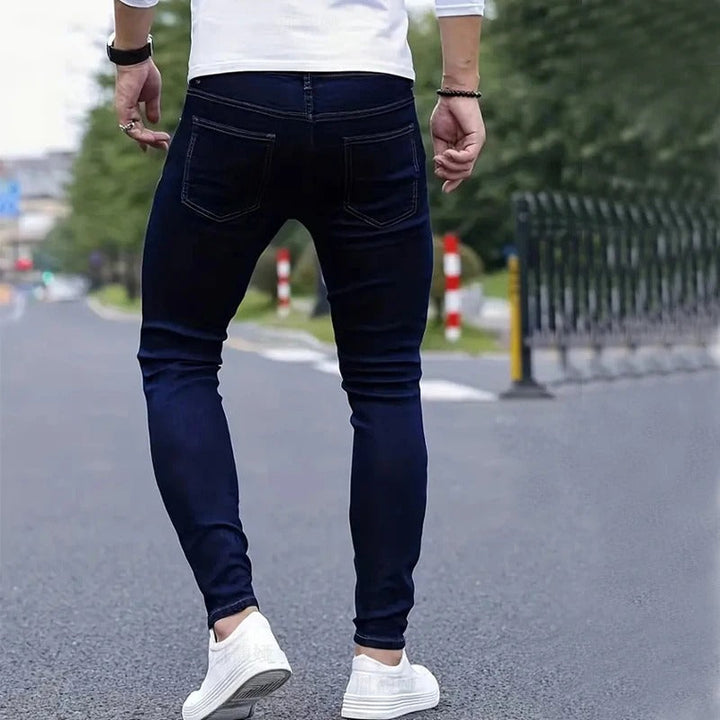 Bakside av menns skinny-jeans i blått, fremhever slim fit og stretch-materiale som gir en komfortabel silhuett.