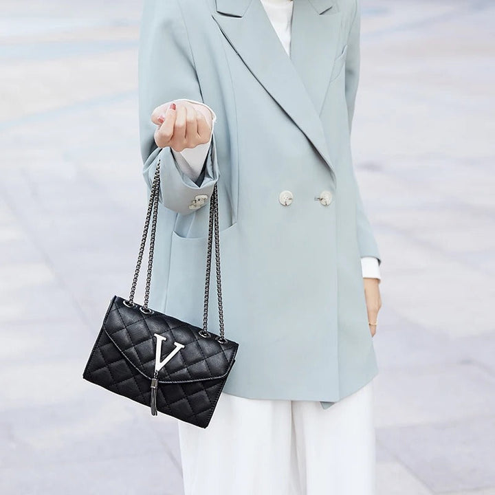 Trendy vattert dameveske i crossbody-modell med dusker. Tilgjengelig i svart og hvit, rutete stil.