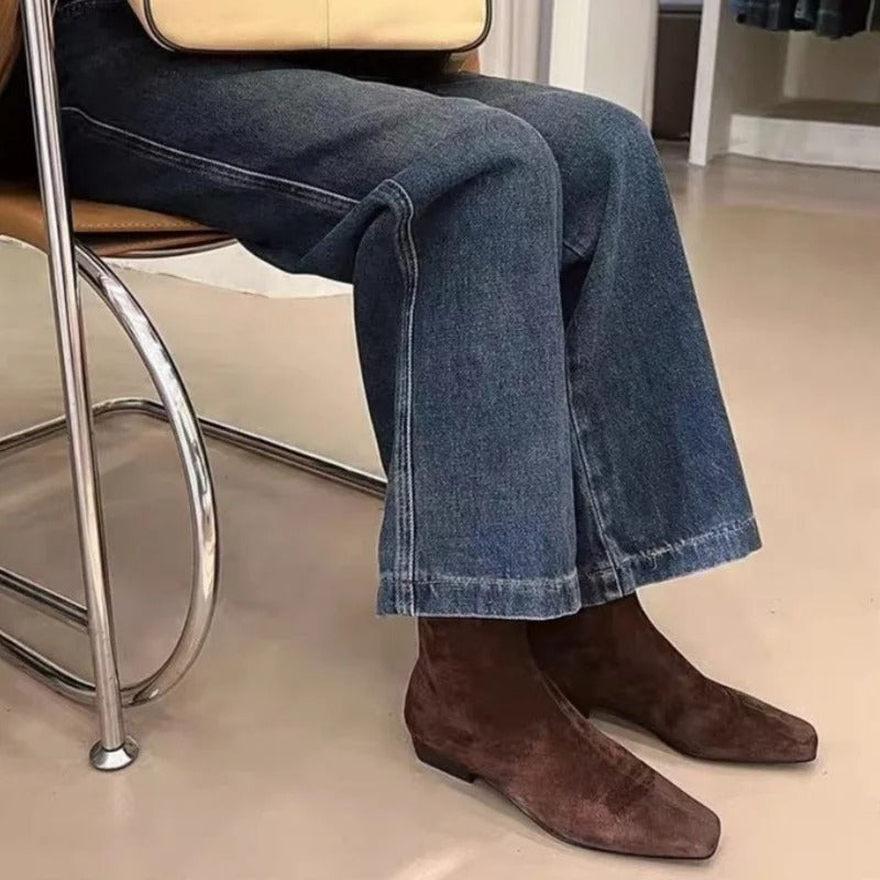 En kvinne bærer stilige svarte ankelstøvletter. Trendy og komfortable vinterstøvler med lav hæl.
