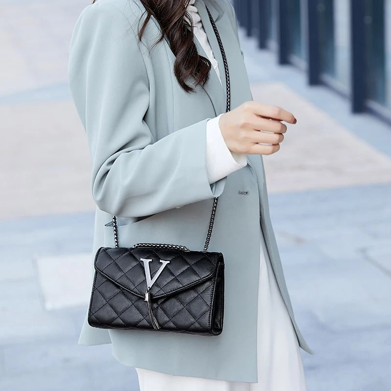 Praktisk svart vattert crossbody veske for dame, med fine dusker. Elegant rutete skulderveske.