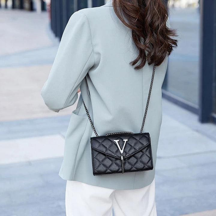 Motebevisst vattert crossbody veske i hvit med dusker. Elegant og praktisk dameveske til fest.