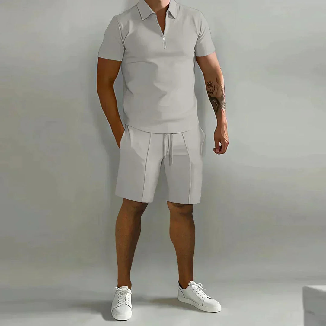 Mann iført et casual sommersett med glidelåspolo og shorts, viser passform og stil.