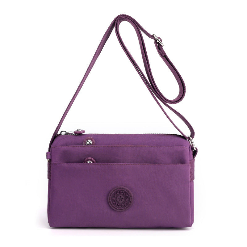 Bakside av lettvekt crossbody-veske i nylon med justerbar stropp for komfortabel bæring.