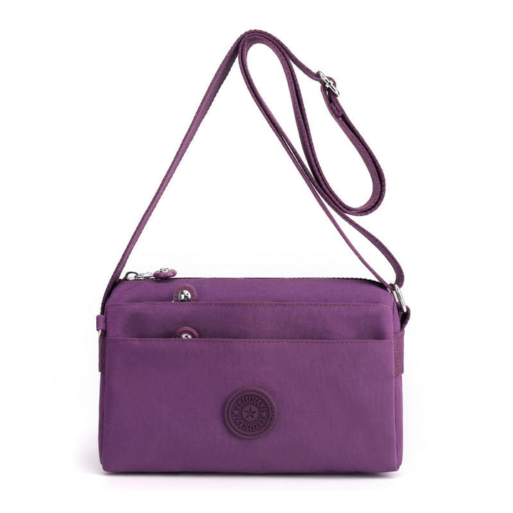 Bakside av lettvekt crossbody-veske i nylon med justerbar stropp for komfortabel bæring.