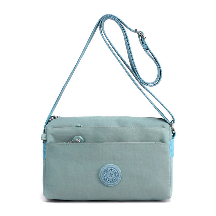 Detalj av slitesterk nylonstoff og solide glidelåser på flerlags crossbody-veske. Ideell for kvinne.
