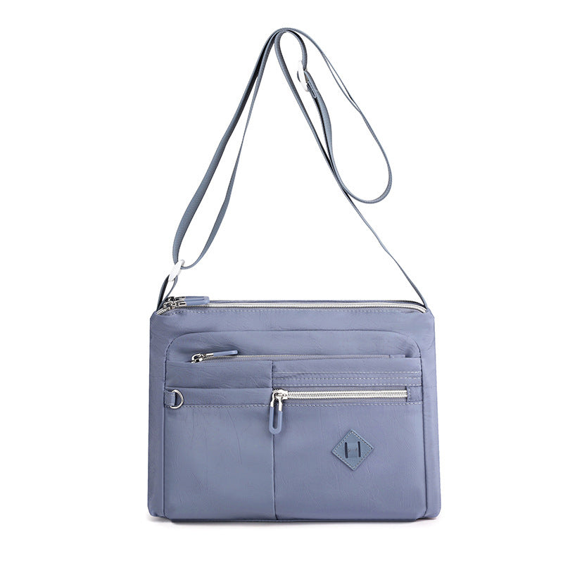 Bilde av en kvinne som bærer en lett nylon crossbody-veske med flere lommer.
