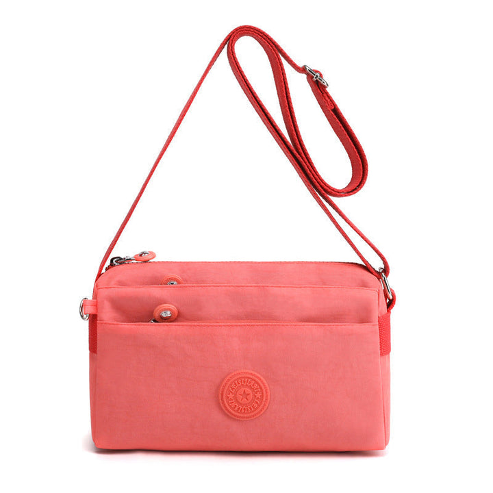 Kvinne bærer stilfull og lettvekt crossbody-veske i nylon. Perfekt som hverdagsveske eller reiseveske.