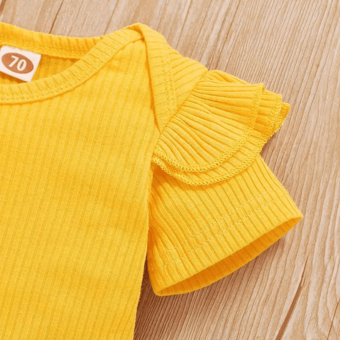 Detaljbilde av solsikkemønster på gult babyklær sett. Stilig og komfortabel babymote.